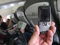 Eine Hand hlt ein ausgeschaltetes Handy in einem Flugzeug.
