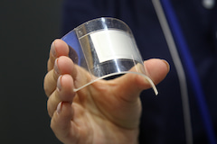 Eine Mietarbeiterin von Panasonic zeigt den Prototypen eines biegbaren Lithium-Ionen-Akkus