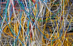 Viele Computer-Kabel stecken in Anschlussbuchsen eines Grorechners.