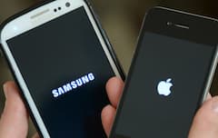 Eine Frau hlt ein Apple iPhone 4s (r) und ein Samsung Galaxy S3 hoch.