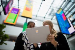 Hannah Kaspar (l) und Pauline Heim, beide Projektstudentinnen im "Change Management" bei Microsoft, blicken im Atrium der neuen Microsoft-Deutschland-Zentrale in Mnchen (Bayern) auf ein Microsoft-Tablet