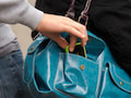 Ein Mann stiehlt einer Frau an einer Bus- und Straenbahnhaltestelle ein Smartphone aus einer Handtasche (gestellte Szene).
