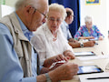 Senioren lernen bei einem Kurs die Verwendung eines Tablets