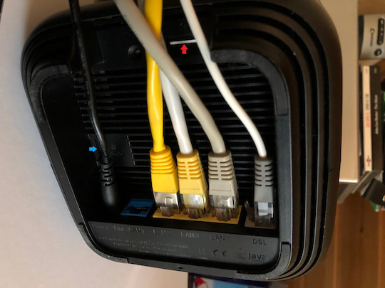 Buchsen auf der Unterseite. Von links: Strom, Bridge/LAN1 (blau), LAN2-4 (gelb) DSL (grau). Slot fr Micro-SIM/Hybrid (roter Pfeil) SD-Speicher (max. 2 TB, blauer Pfeil)
