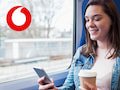 Frau mit Handy und Kaffeebecher im Zug