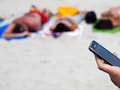 Mit einem Smartphone am Strand sollte man aufpassen